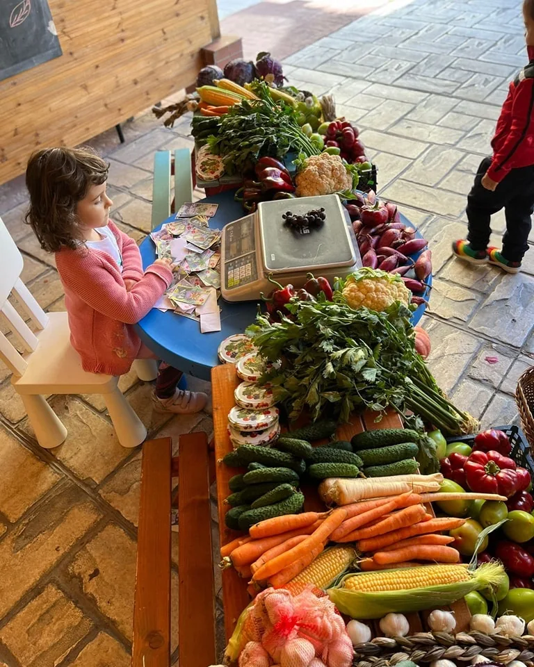 Un copil lângă o masă cu legume, într-o activitate la Fata din Dafin