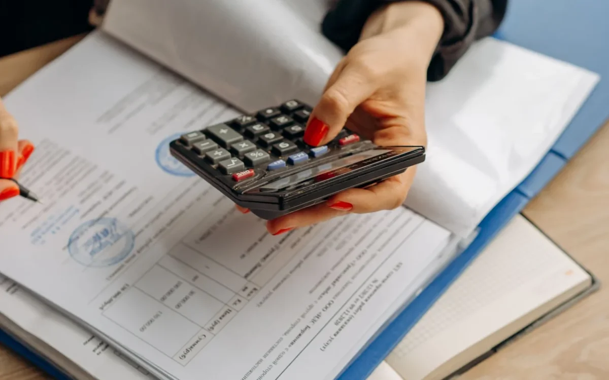 Mâini cu un calculator deasupra unor documente
