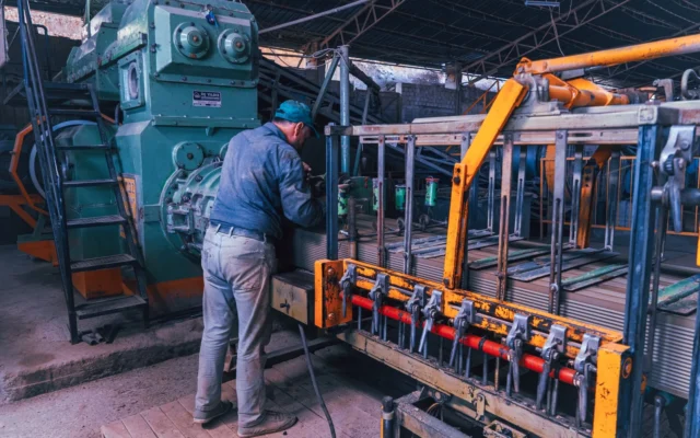 Lucrător lângă un utilaj în interiorul unei fabrici