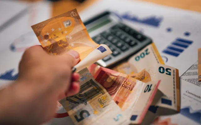 Bancnote euro pe documente financiare lângă un calculator