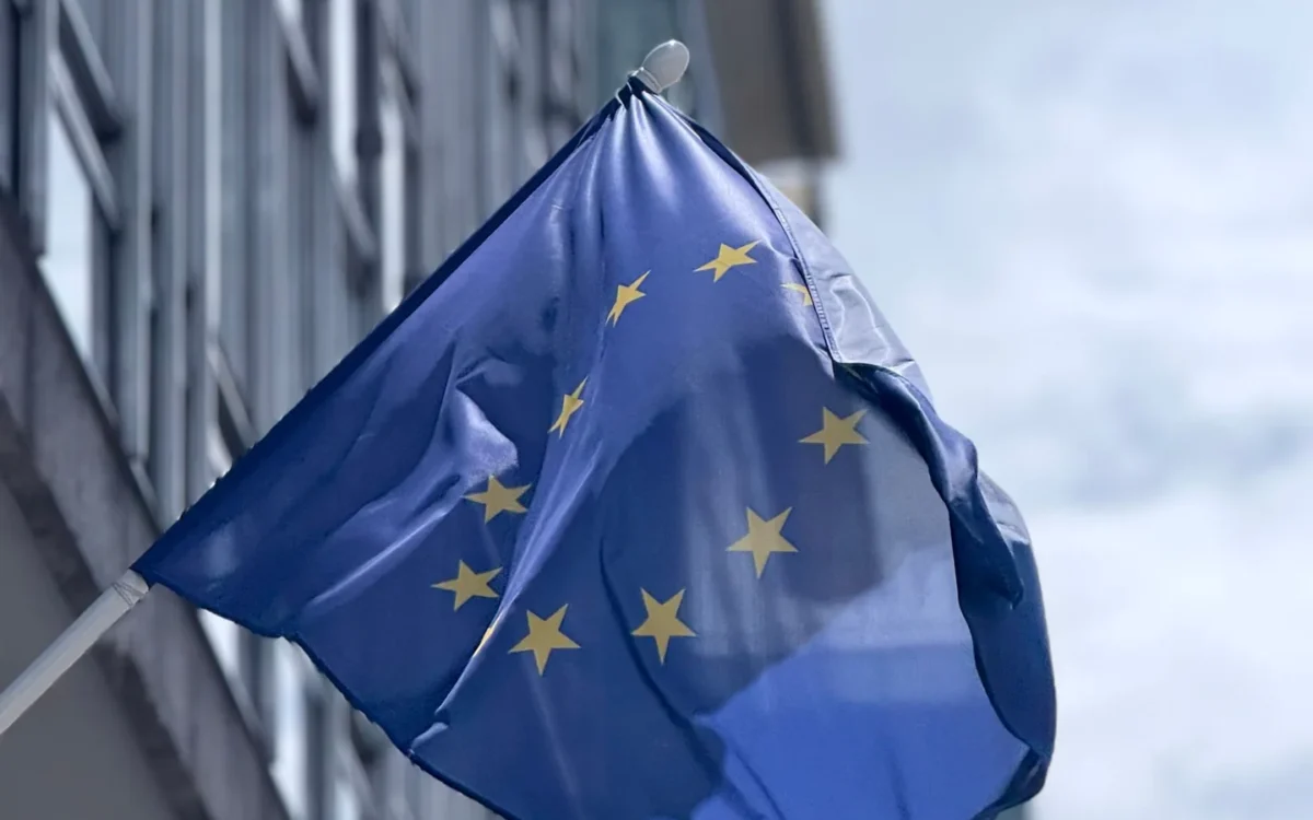 Drapelul Uniunii Europene lângă o fațadă de sticlă