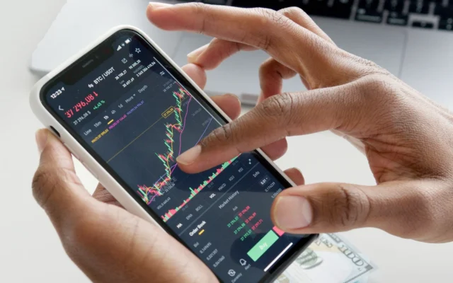 Mâini care folosesc un telefon cu un grafic financiar