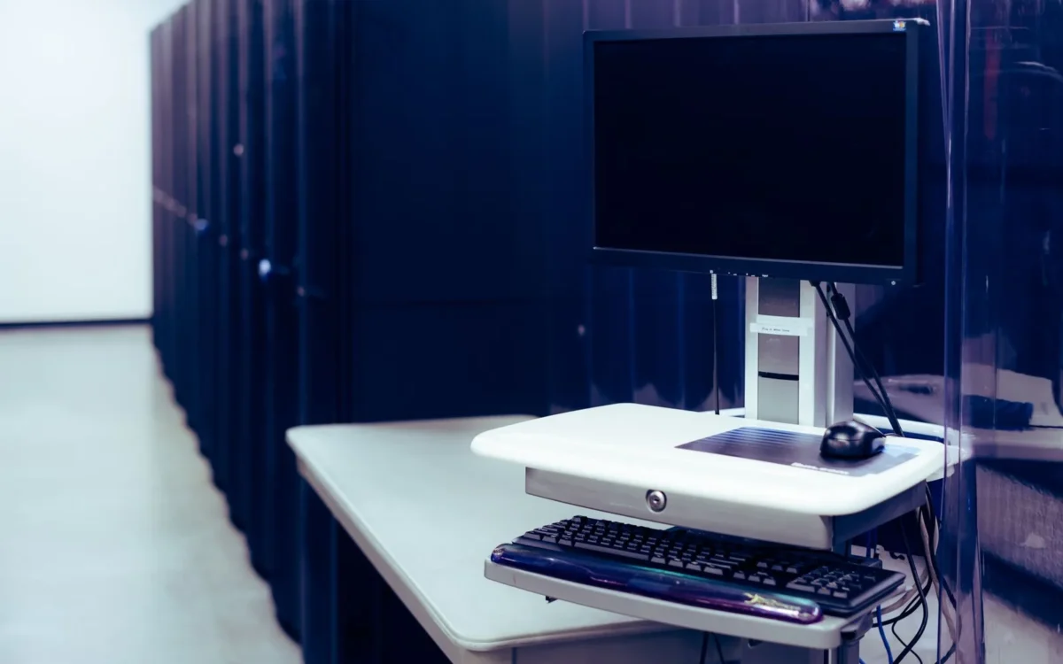 Monitor și tastatură lângă rackuri într-o sală de servere