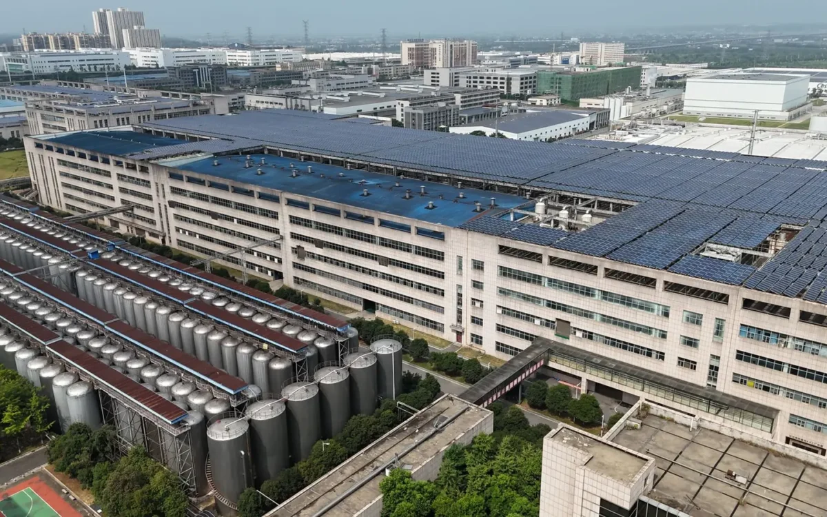Panouri fotovoltaice pe un acoperiș industrial lângă rezervoare