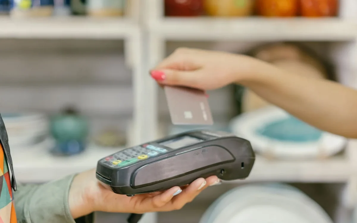 Mână cu un card deasupra unui terminal de plată