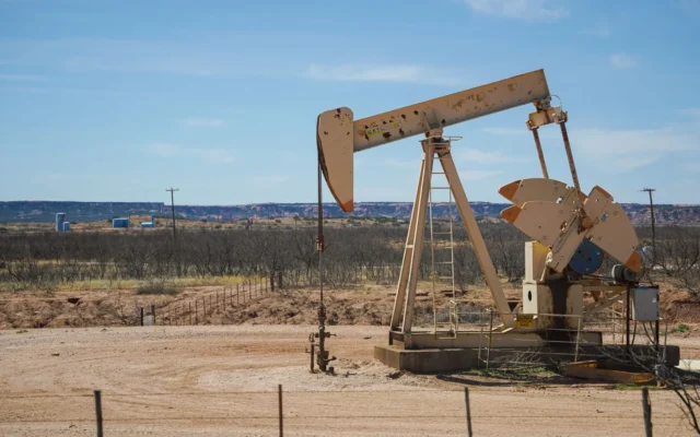 Pompă de extracție a țițeiului pe un teren arid, sub cer albastru