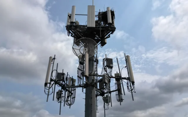 Turn de telecomunicații cu antene albe și cabluri, pe un cer cu nori